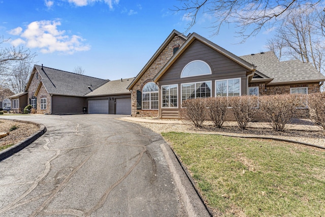 view of front of home with an attached garage, stone siding, driveway, and roof with shingles