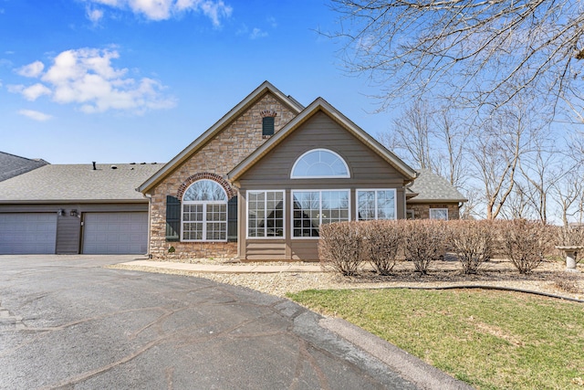 view of front of house featuring aphalt driveway, brick siding, a garage, and roof with shingles