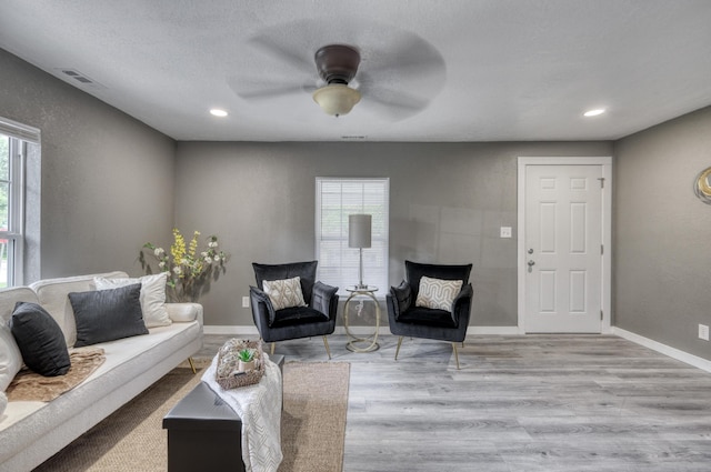 living room with recessed lighting, visible vents, baseboards, and wood finished floors