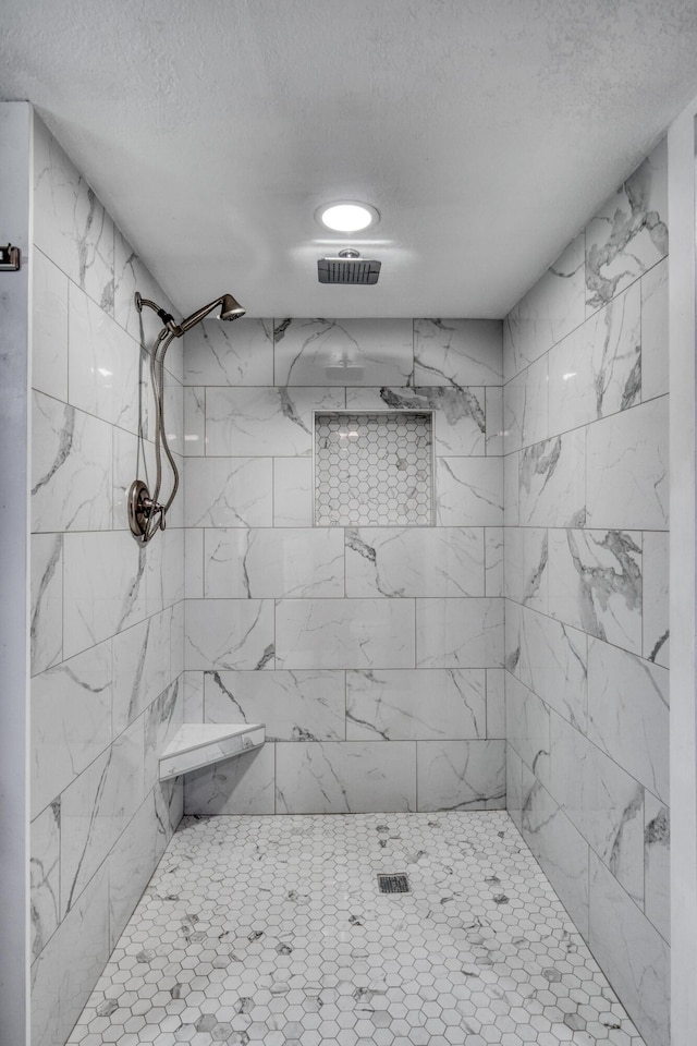 full bathroom with visible vents, tiled shower, and a textured ceiling