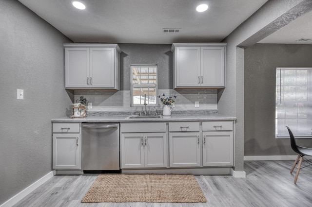 kitchen with a sink, visible vents, stainless steel dishwasher, and a textured wall