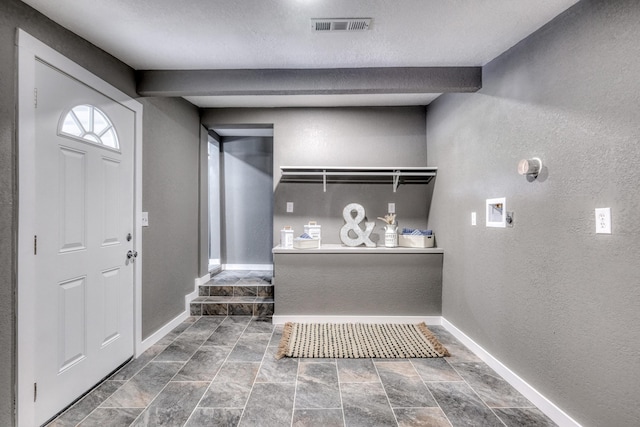 foyer with visible vents, baseboards, a textured ceiling, and a textured wall