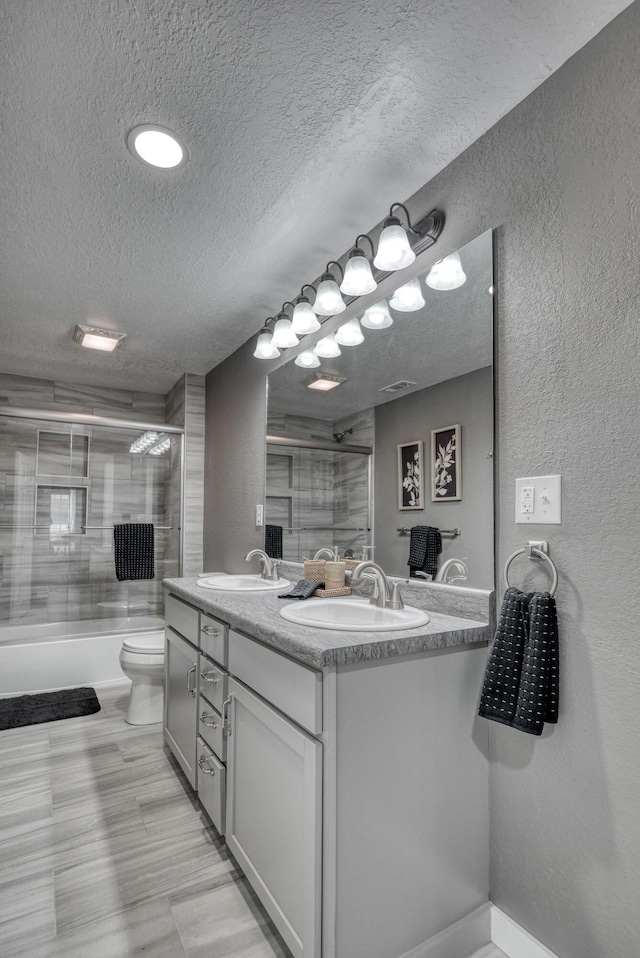 bathroom with double vanity, a textured ceiling, a textured wall, and a sink