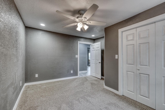 unfurnished bedroom with a textured wall, a closet, carpet floors, and a textured ceiling