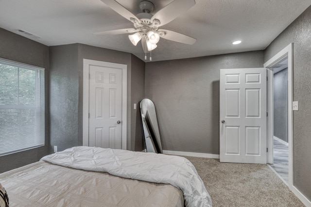 carpeted bedroom featuring visible vents, baseboards, a textured wall, a textured ceiling, and a ceiling fan