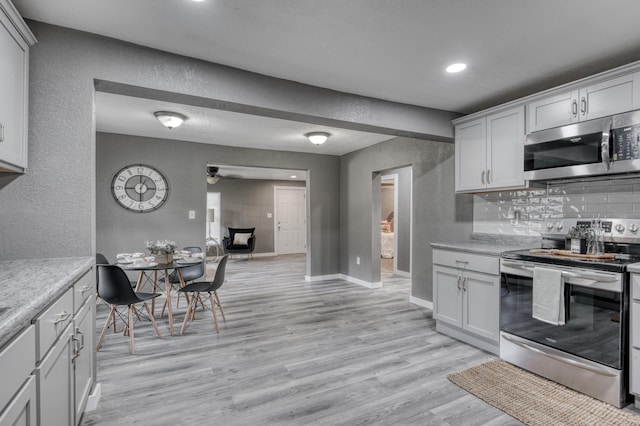 kitchen featuring backsplash, appliances with stainless steel finishes, light wood-style flooring, and light countertops