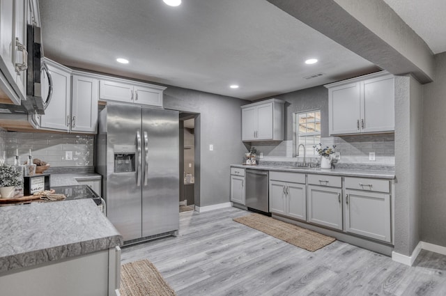 kitchen featuring baseboards, visible vents, a sink, stainless steel appliances, and light wood-style floors