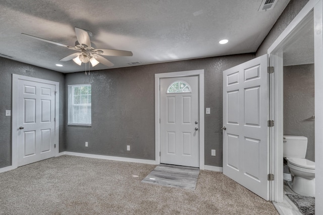 carpeted foyer entrance featuring baseboards, a textured wall, visible vents, and a textured ceiling