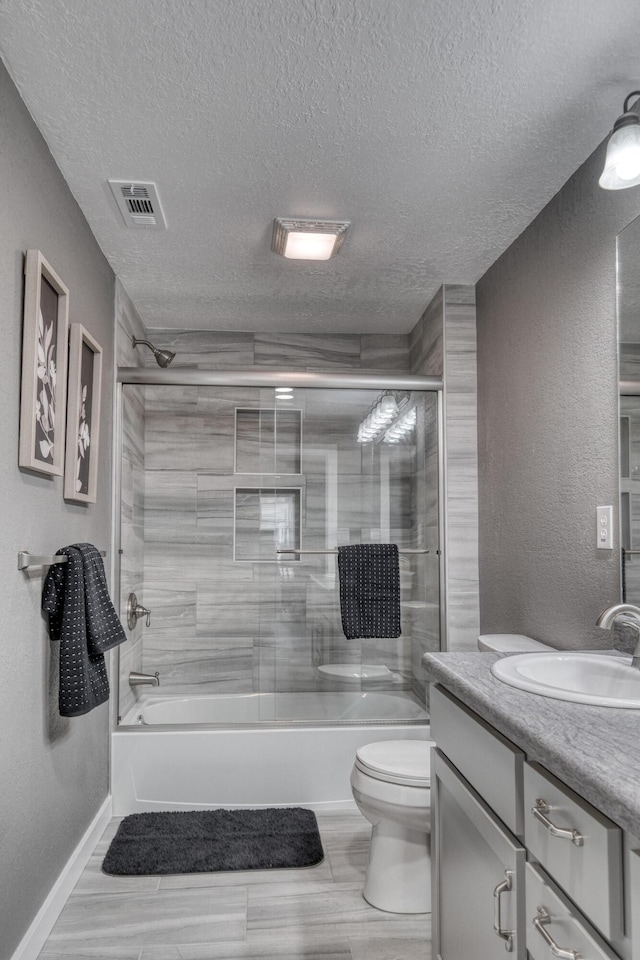 bathroom featuring visible vents, toilet, a textured ceiling, enclosed tub / shower combo, and vanity