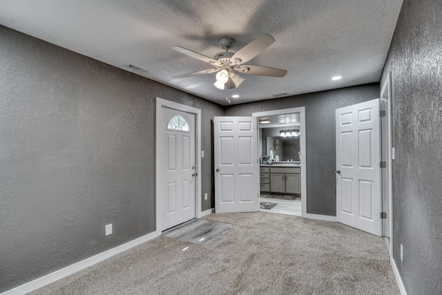 entryway featuring light carpet and a textured wall