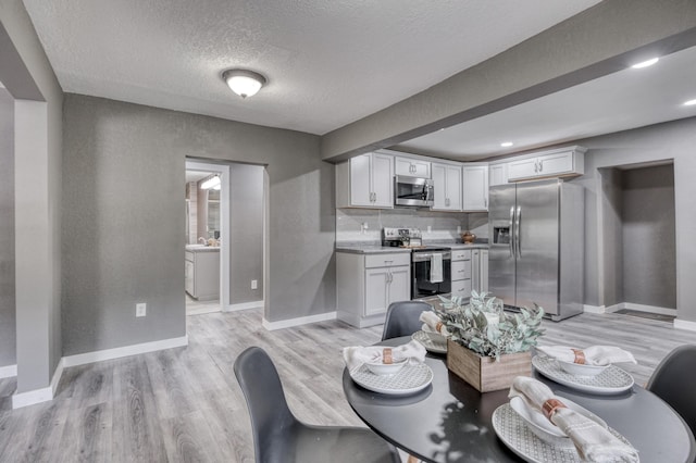 dining space featuring light wood-style flooring, a textured ceiling, recessed lighting, baseboards, and a textured wall