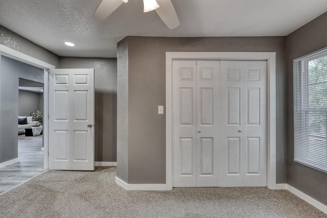 unfurnished bedroom featuring baseboards, carpet floors, a closet, a textured ceiling, and a textured wall