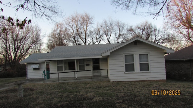 ranch-style home with roof with shingles and a front lawn