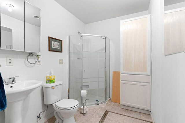 bathroom with toilet, a stall shower, and tile patterned flooring