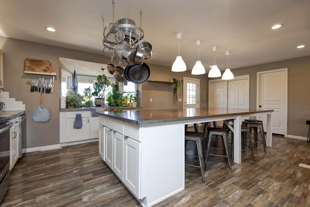 kitchen featuring a kitchen island, dark wood-style floors, recessed lighting, a breakfast bar area, and white cabinets