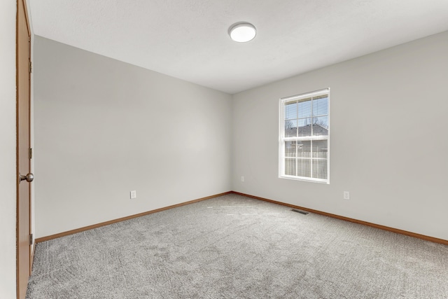 carpeted spare room with visible vents and baseboards