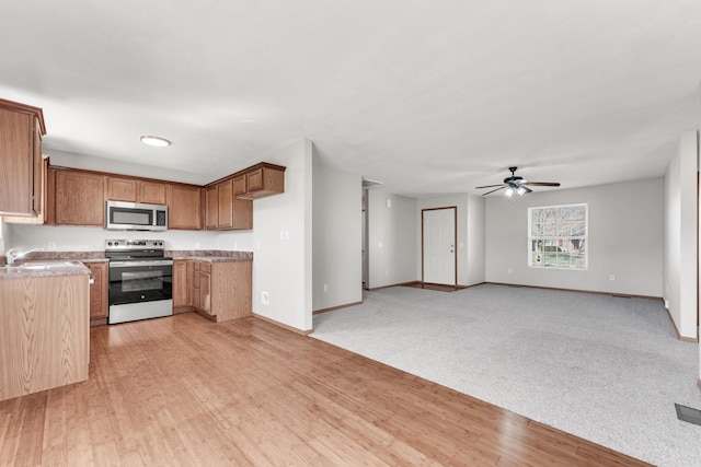 kitchen featuring brown cabinetry, light wood-style flooring, appliances with stainless steel finishes, and light countertops