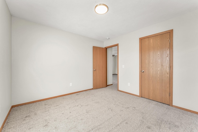 unfurnished bedroom featuring carpet, baseboards, and a closet