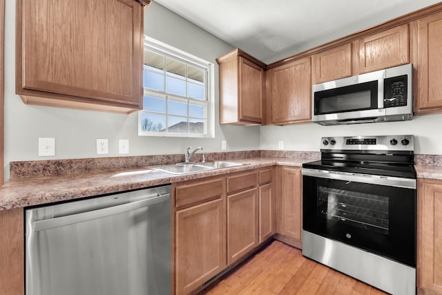 kitchen featuring light wood-type flooring, appliances with stainless steel finishes, and a sink