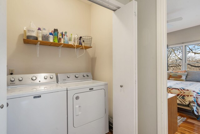 clothes washing area featuring laundry area, washer and dryer, and wood finished floors