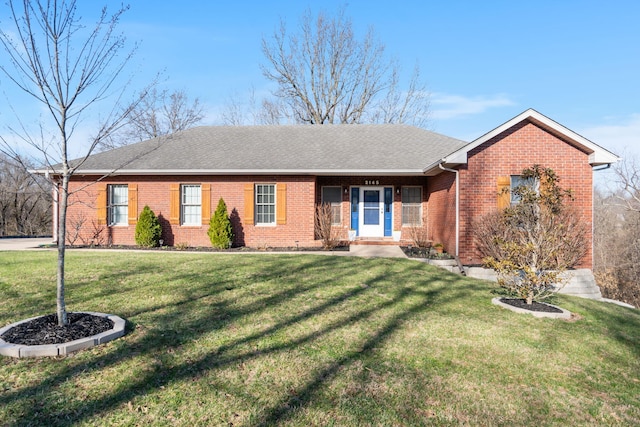 ranch-style house featuring brick siding, a front yard, and roof with shingles