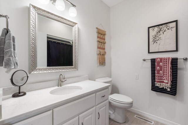 bathroom featuring vanity, toilet, baseboards, and visible vents