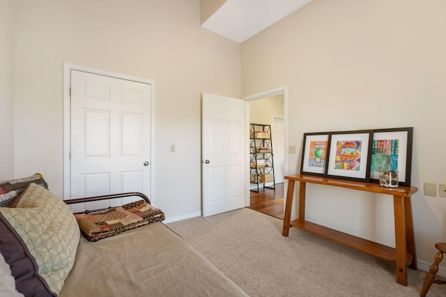 carpeted bedroom with baseboards and a high ceiling