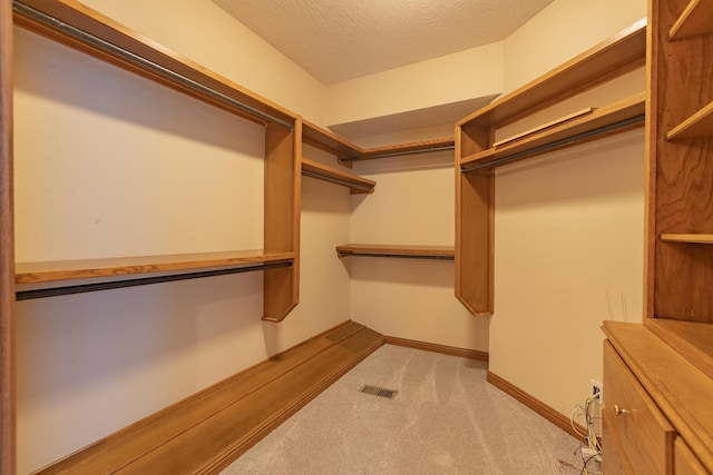 walk in closet with visible vents and light colored carpet