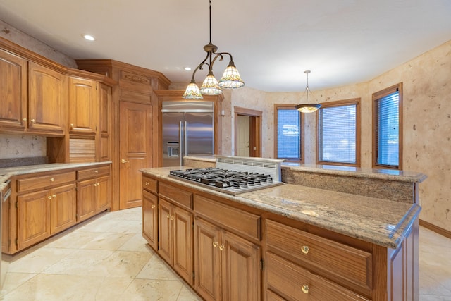 kitchen featuring pendant lighting, appliances with stainless steel finishes, a kitchen island, and brown cabinets