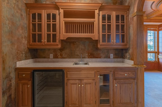 kitchen with a sink, light colored carpet, beverage cooler, and light countertops