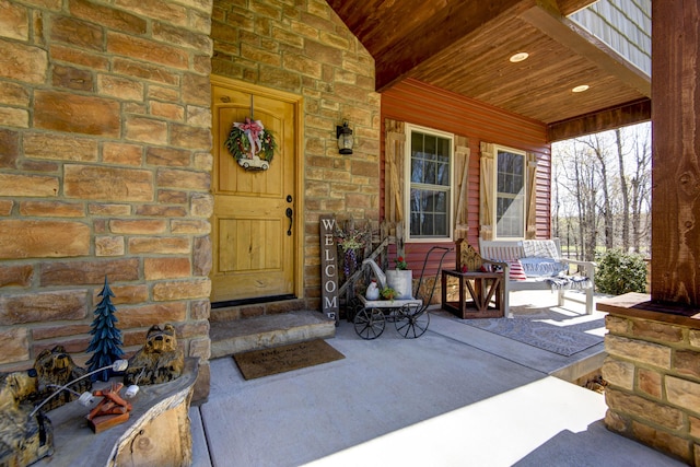 entrance to property with a porch and stone siding