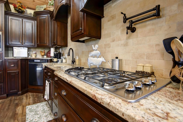 kitchen with dark brown cabinets, light stone countertops, decorative backsplash, stainless steel gas stovetop, and dark wood-style flooring