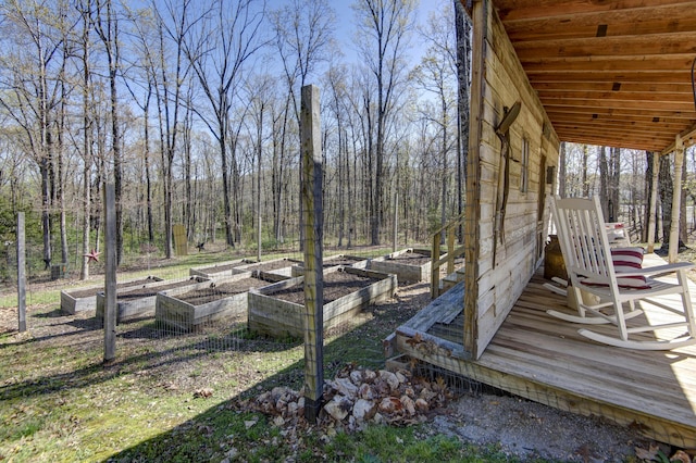 wooden deck with a wooded view and a vegetable garden