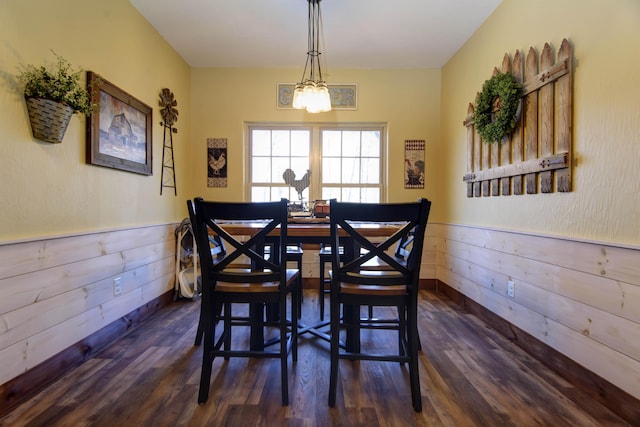 dining room featuring wooden walls, wainscoting, and dark wood-type flooring