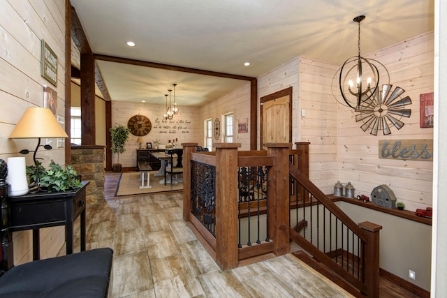 hall featuring light wood-type flooring, an upstairs landing, and a notable chandelier