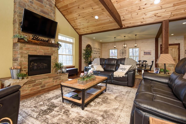 living area featuring a wealth of natural light, beam ceiling, wood ceiling, and a stone fireplace