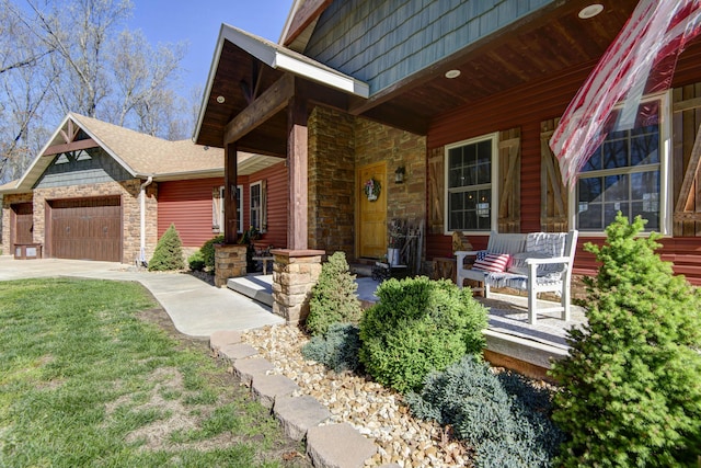 exterior space featuring a porch, concrete driveway, a yard, stone siding, and an attached garage