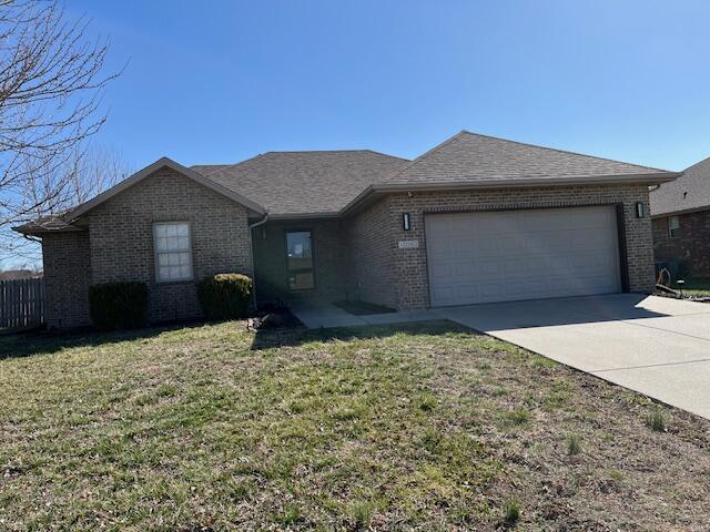 ranch-style house featuring a front lawn, brick siding, and an attached garage