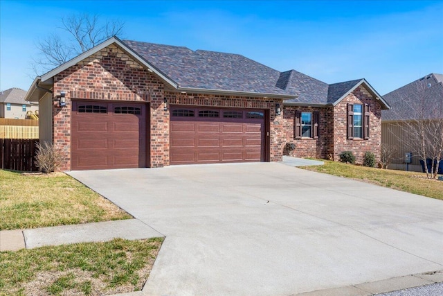 ranch-style home with driveway, brick siding, an attached garage, and fence