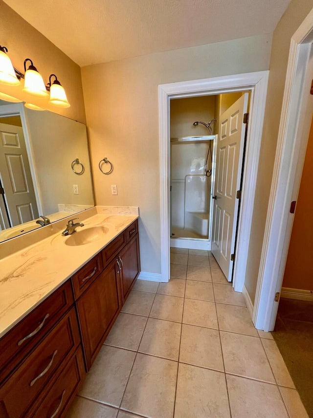 bathroom with baseboards, a stall shower, vanity, and tile patterned flooring