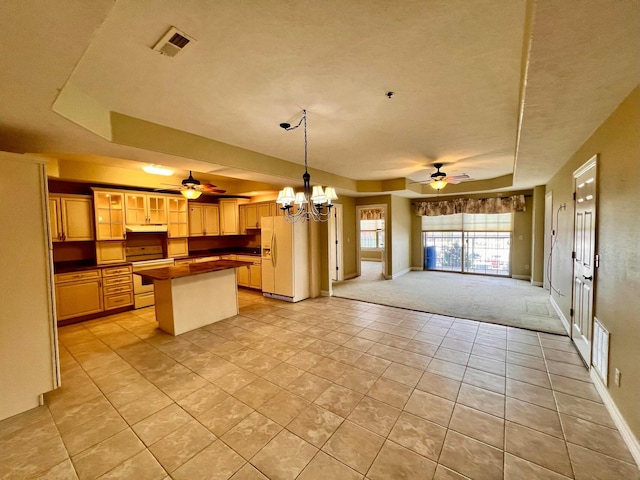 kitchen with visible vents, white appliances, a kitchen island, and open floor plan