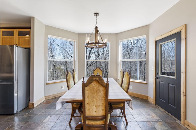 dining room featuring stone tile floors, a healthy amount of sunlight, and baseboards