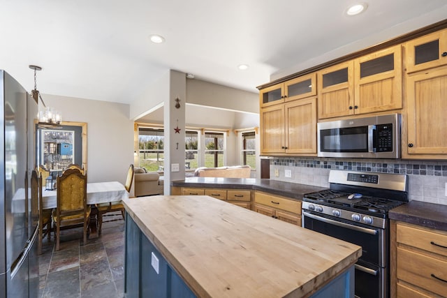 kitchen with tasteful backsplash, a kitchen island, butcher block countertops, stone tile floors, and appliances with stainless steel finishes