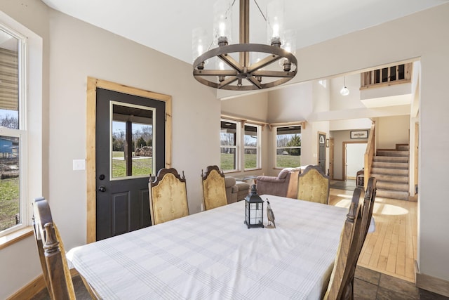 dining space with baseboards, an inviting chandelier, and stairs