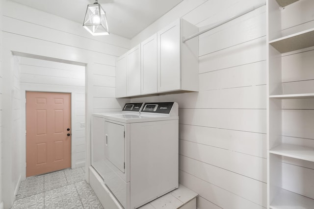 laundry room featuring cabinet space, washing machine and dryer, wood walls, and light tile patterned flooring