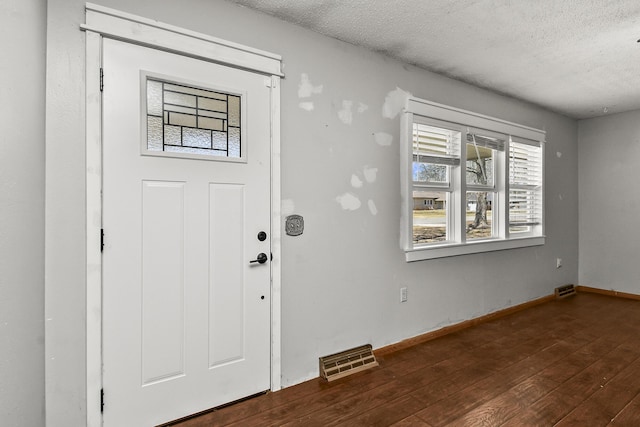 entrance foyer featuring visible vents, baseboards, a textured ceiling, and hardwood / wood-style flooring