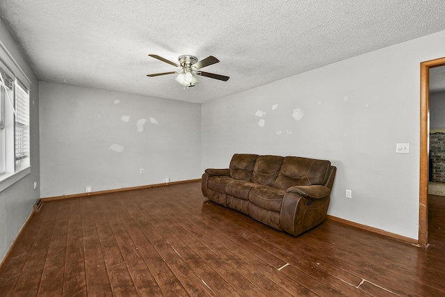 living room featuring a textured ceiling, a ceiling fan, baseboards, and wood-type flooring