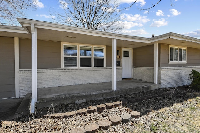 entrance to property featuring brick siding and covered porch