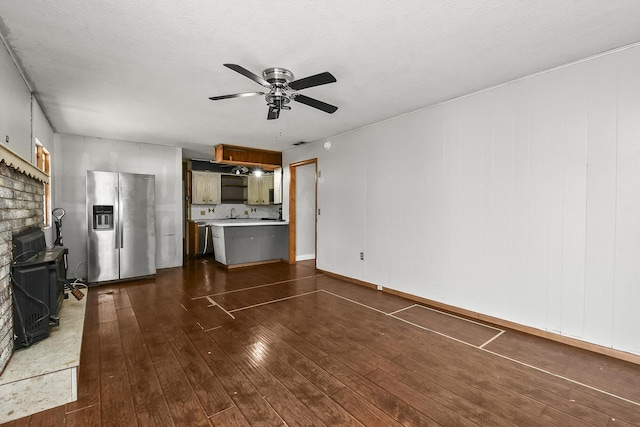 unfurnished living room with dark wood finished floors, a textured ceiling, a fireplace, and ceiling fan