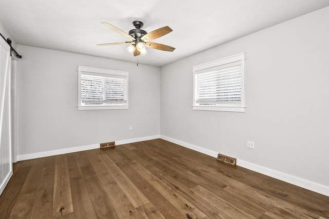 unfurnished room featuring a barn door, plenty of natural light, baseboards, and ceiling fan